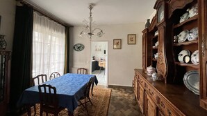 Een eetkamer met een tafel voor vier personen, een houten kast met servies en een kroonluchter.