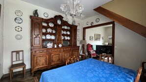 Een slaapkamer met een bed, een houten dressoir en een kroonluchter.