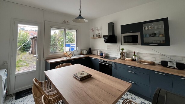 Een moderne keuken met een houten eettafel, inbouwapparatuur en uitzicht door het raam.
