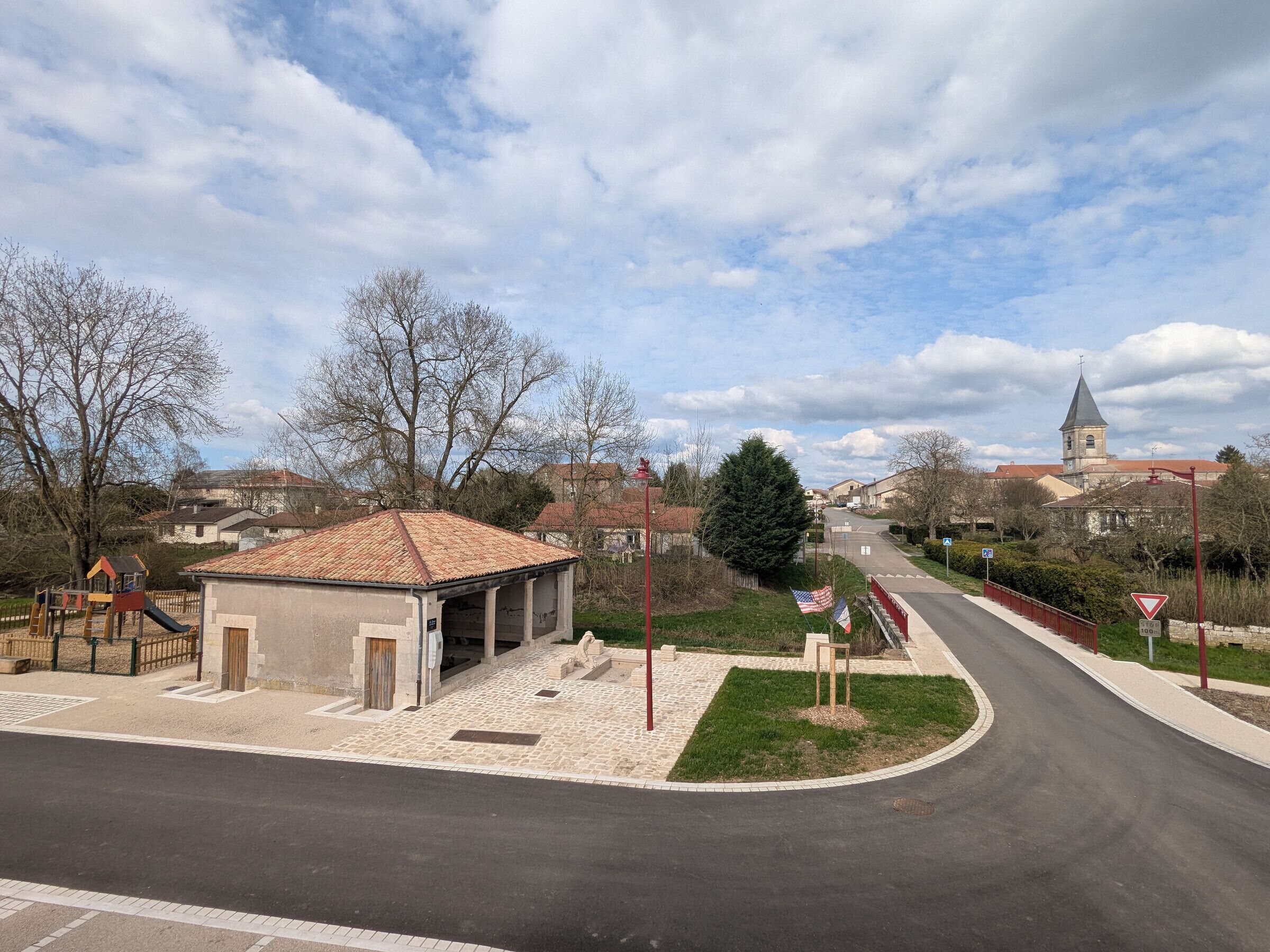 A street view with a playground, a small building, and a church in the background.