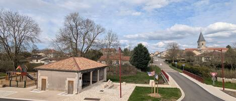 A street view with a playground, a small building, and a church in the background.