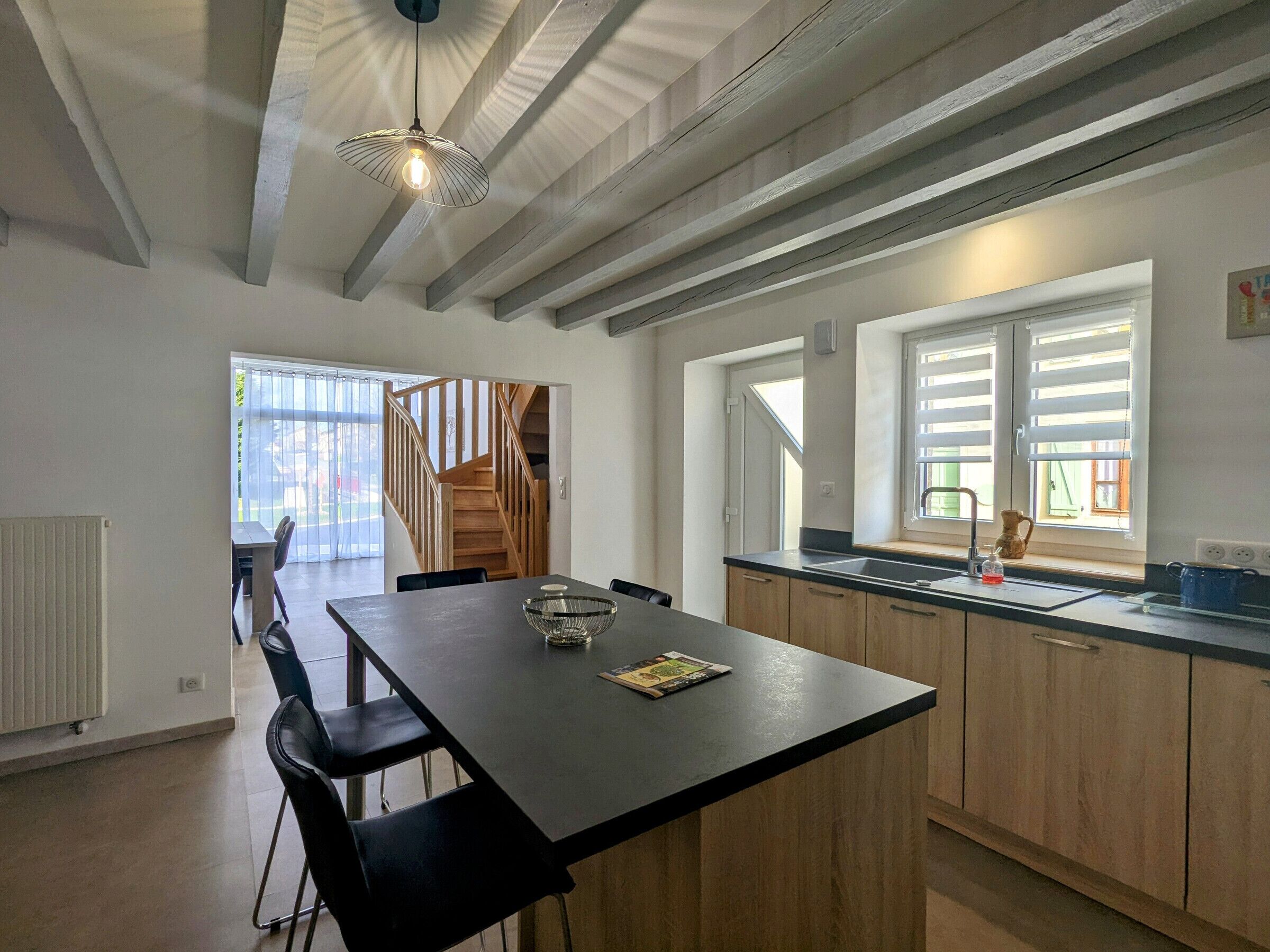 A modern kitchen with a central island, wooden cabinets, and a window with blinds.