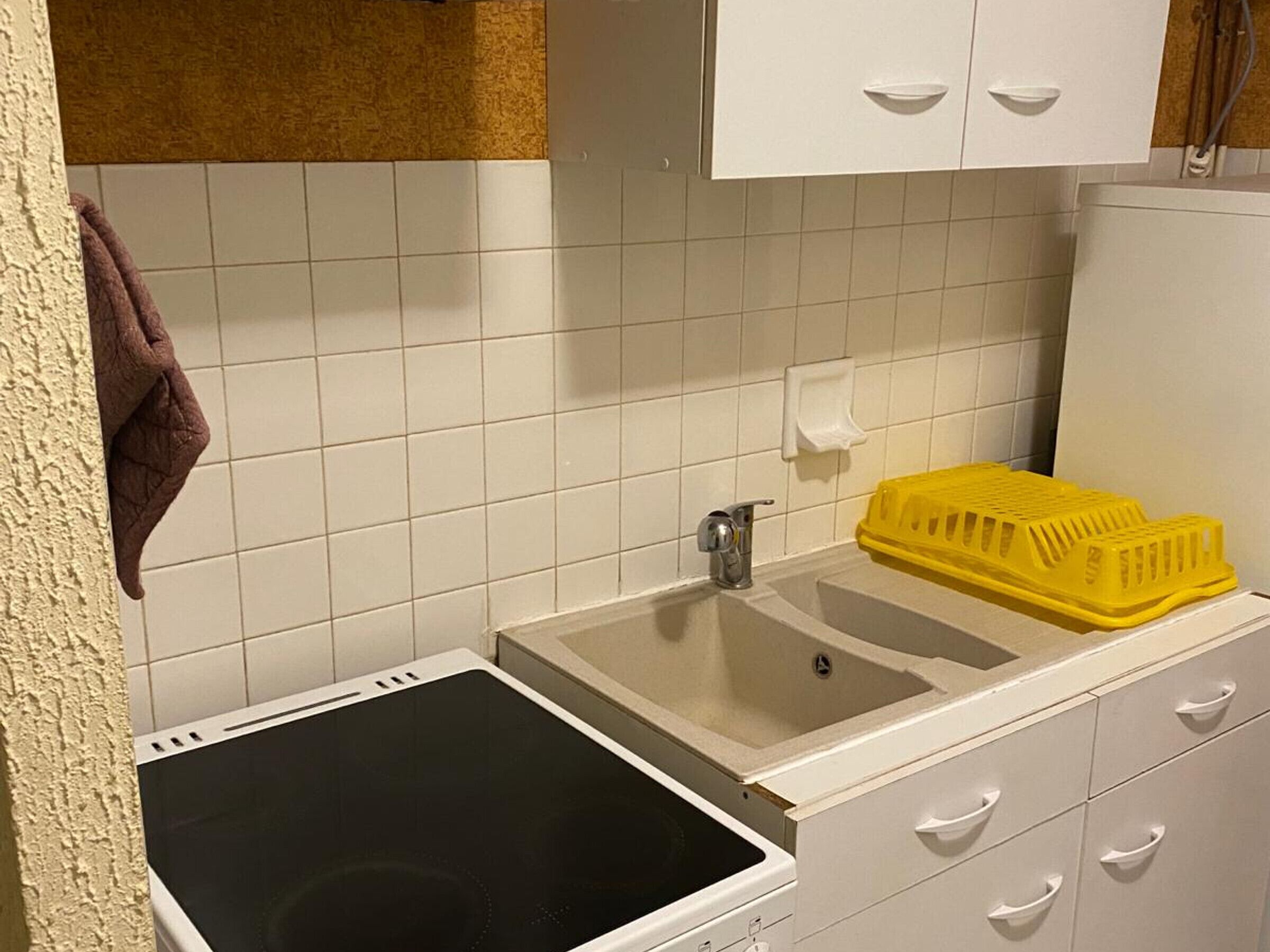 A small kitchen with white cabinets, a sink, and a stove.