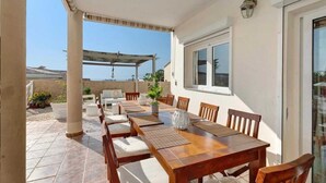 A covered patio with a wooden table and chairs, a pergola, and a view of the sea. - Villa Luxury el Mirador (Adeje)