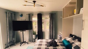 A bedroom with a bed, a TV, a desk, and a wardrobe. - Modern Grenada Studio with Mountain Views & Free Parking (Saint George's)