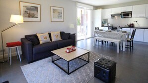 A modern living room with a sofa, coffee table, and a dining area with a table and chairs. - Modern 51m² Apartment in Luchon - 4 pers, Terrace, Parking (Bagnères-de-Luchon)