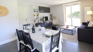 A modern living room with a sofa, a coffee table, and a dining area with a table set for a meal. - Modern 51m² Apartment in Luchon - 4 pers, Terrace, Parking (Bagnères-de-Luchon)