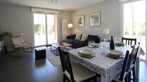 A modern living room with a dining area, featuring a sofa, a coffee table, and a dining table set for two. - Modern 51m² Apartment in Luchon - 4 pers, Terrace, Parking (Bagnères-de-Luchon)