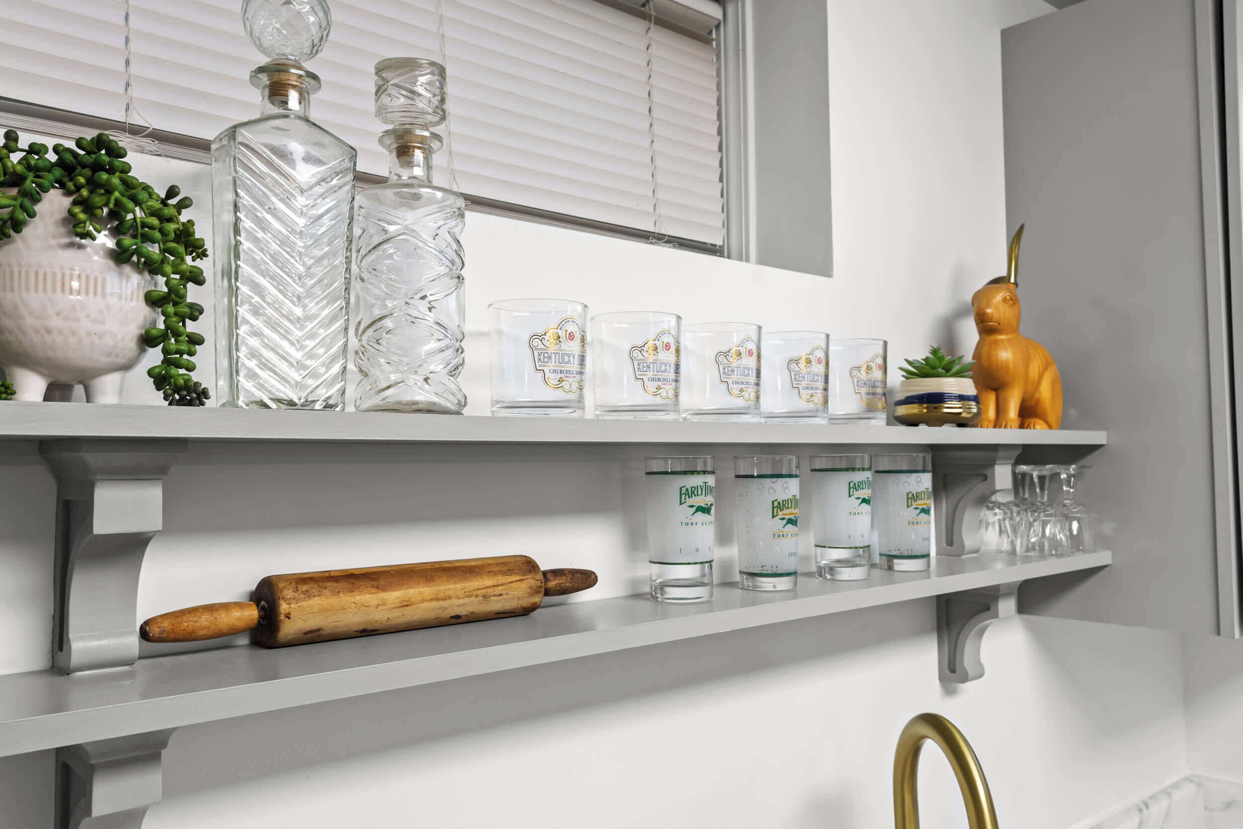 Una repisa de cocina con cristalería, un rodillo y una figurita decorativa de animal.