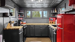 Una cocina moderna con muebles oscuros, un refrigerador rojo y una encimera de madera.