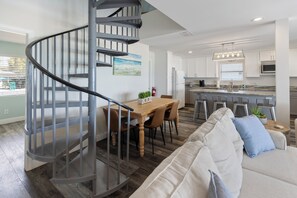 A modern kitchen with white cabinets, a stainless steel refrigerator, and a bar area.