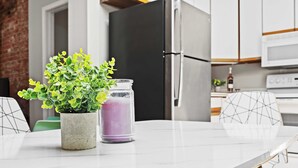 Una cocina moderna con encimera de mármol, una planta en maceta y un recipiente morado.