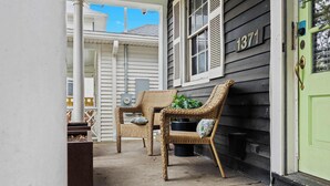 A porch with wicker furniture and a green door.