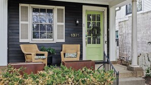 A house with a green door, two wicker chairs, and a mailbox.