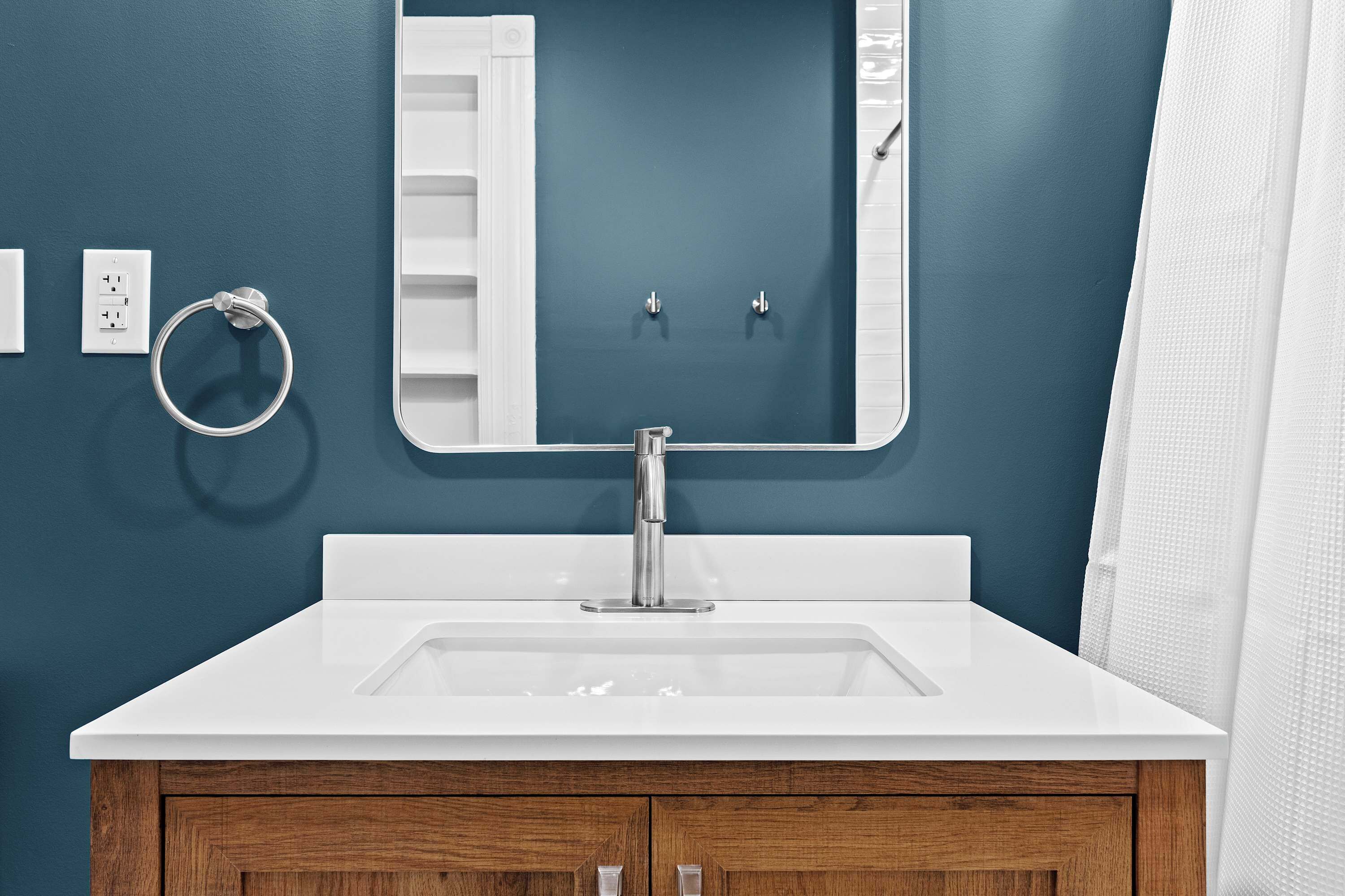 A bathroom with a white sink, a mirror, and wooden cabinets.