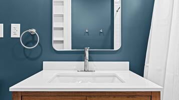 A bathroom with a white sink, a mirror, and wooden cabinets.