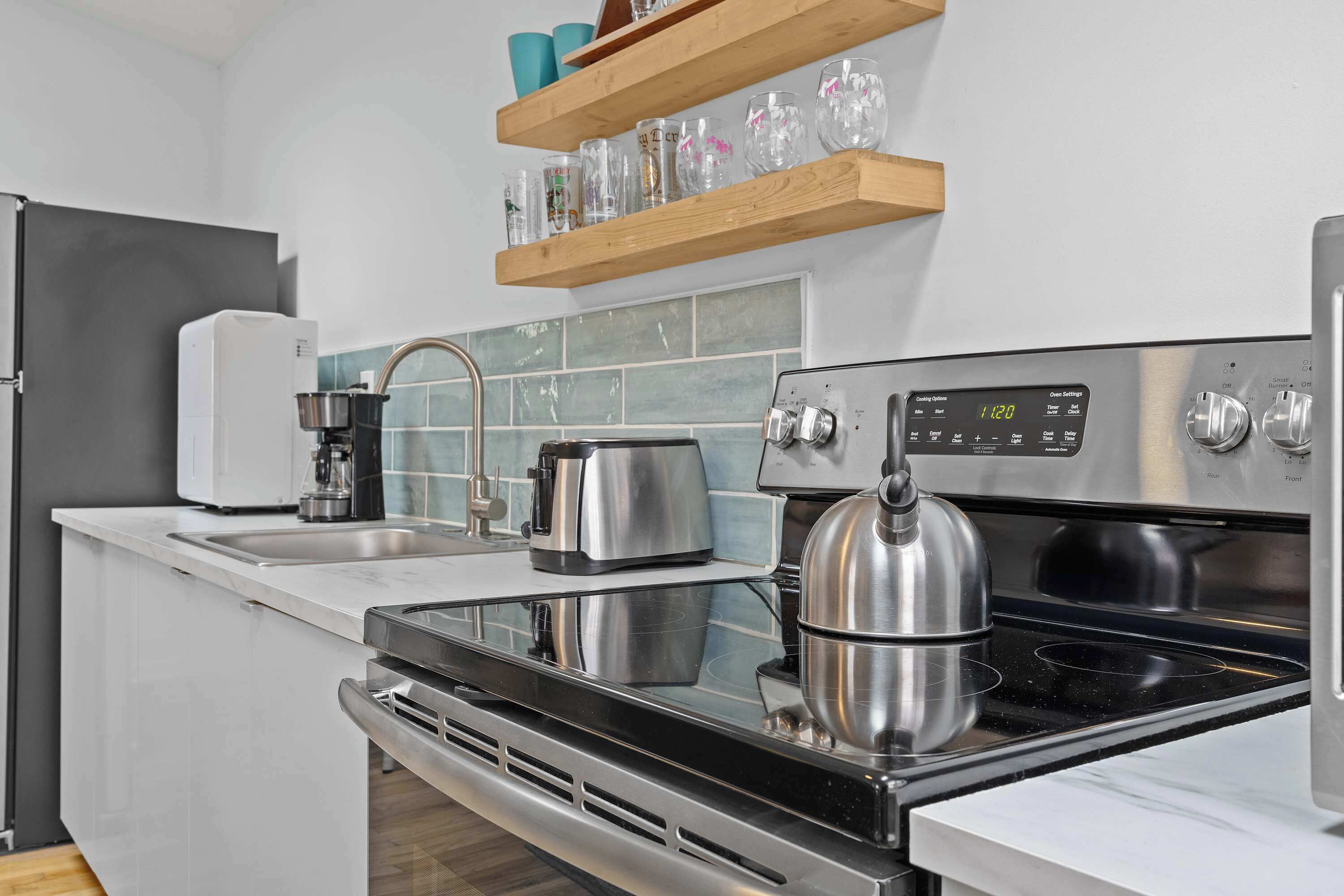 A modern kitchen with a stainless steel stove, a coffee maker, and a kettle.