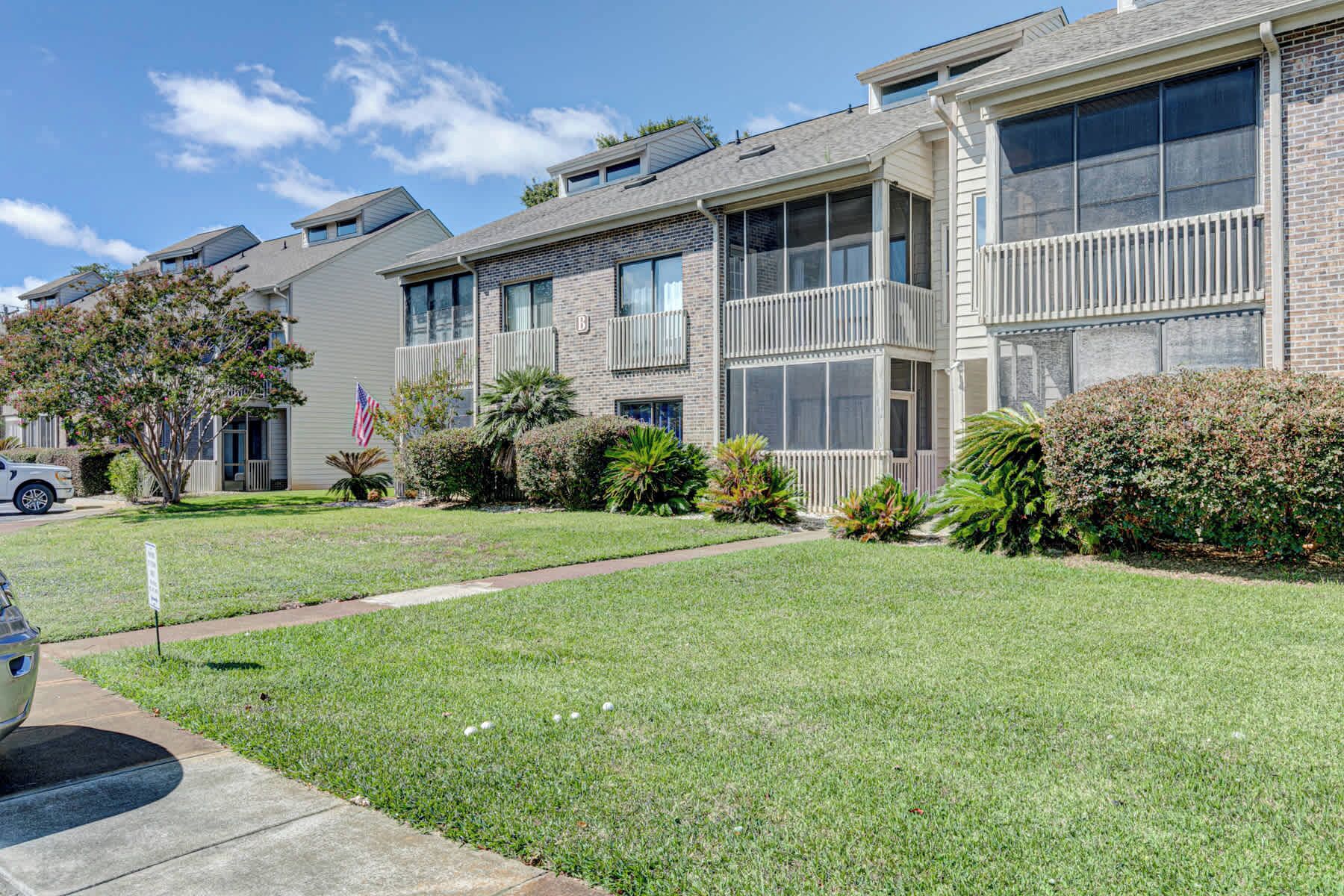 A residential building with a brick facade, multiple windows, and a well-maintained lawn.