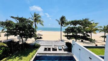 Ein Poolbereich mit Blick auf einen Strand und Palmen.