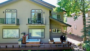 Ein zweistöckiges Haus mit Terrasse, Sitzgelegenheiten im Freien und einem Whirlpool.