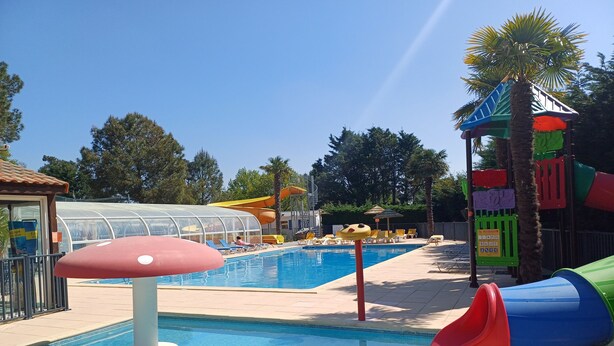 A swimming pool with a slide, lounge chairs, and a covered area. - Mobilhome saint hilaire de riez in 4 star campsite (Saint-Hilaire-de-Riez)