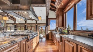 A spacious kitchen with wooden cabinets, a large island, and a view of the outdoors. - Ski-in/ski-out luxe Colony chalet, views, hot tub, game room! (Park City)