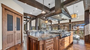 A spacious kitchen with wooden cabinetry, a large island, and a stone backsplash. - Ski-in/ski-out luxe Colony chalet, views, hot tub, game room! (Park City)