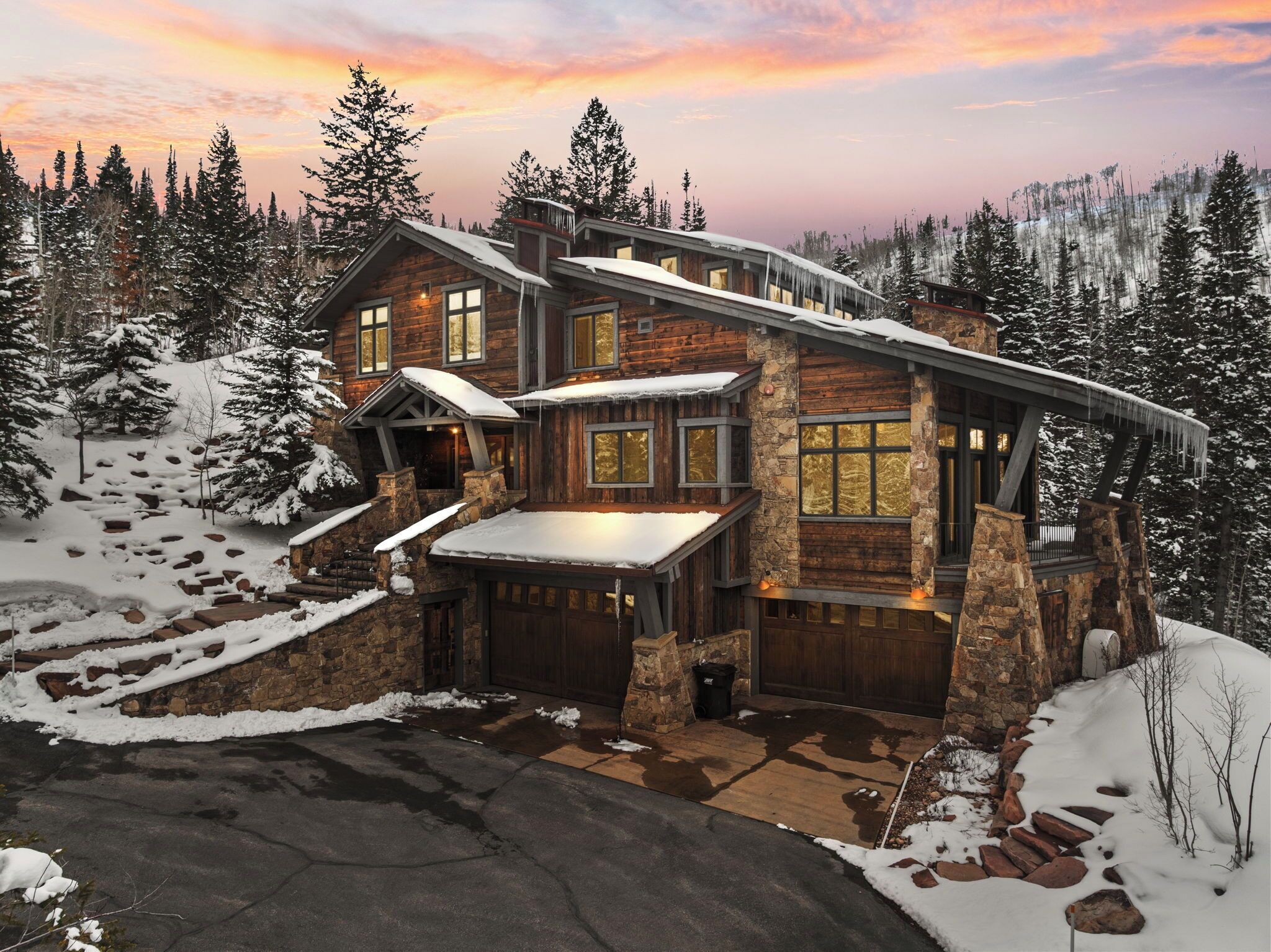 A log cabin with a stone foundation, multiple windows, and a covered porch.