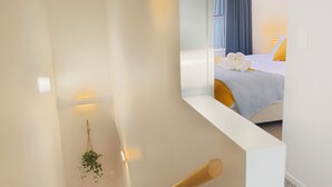 Habitación de hotel moderna con cama, una mesita de noche y una ventana con cortinas.