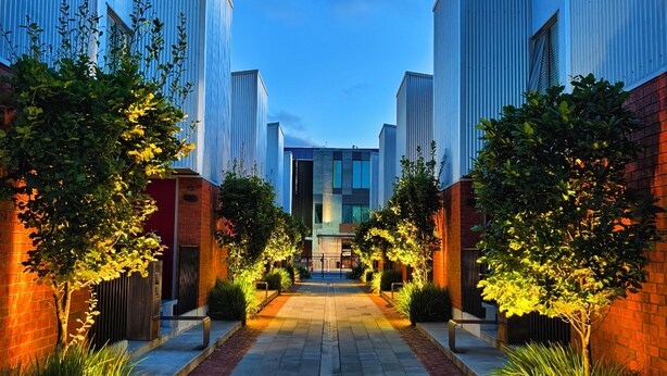 A pathway flanked by modern buildings with a central open space.