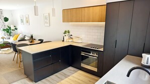 A modern kitchen with a central island, built-in oven, and a stainless steel sink.