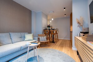 Uma sala de estar moderna com um sofá, uma mesa de centro e uma área de jantar com cadeiras e uma mesa.