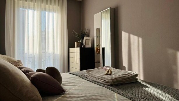 A bedroom with a bed, a dresser, a mirror, and a window with sheer curtains. - Millenium Apartment (Redondela)