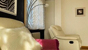 A room with a fur-covered sofa, a massage chair, and a zebra-patterned curtain. - Millenium Apartment (Redondela)