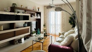 A modern living room with a sofa, a glass coffee table, a TV, and a bookshelf. - Millenium Apartment (Redondela)