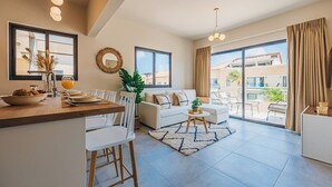 A modern living room with a dining area, large windows, and a balcony.