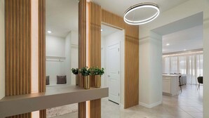 Un interior moderno con un mostrador de recepción de madera, una puerta y una zona de cocina al fondo.