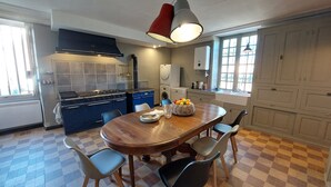Una cocina con una mesa de madera, sillas, estufa y lavadora.