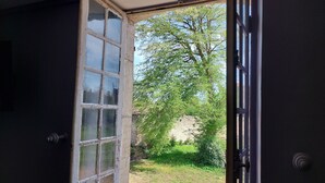 Puerta abierta con vista a un jardín y un muro de piedra.