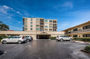 Un hôtel à plusieurs étages avec un parking situé devant.