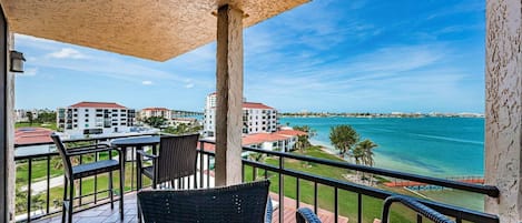 Ein Balkon mit Korbmöbeln, Blick auf den Ozean und Gebäude im Hintergrund.