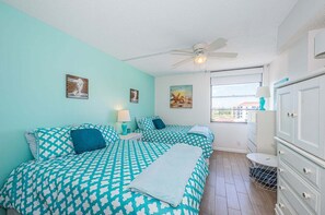 Een kamer met twee bedden, een plafondventilator, een raam met uitzicht en een dressoir.