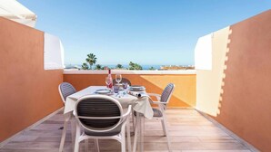 A terrace with a table set for two, overlooking a coastal view. - Tenerife Royal Gardens 23 - One Bed (Playa de las Américas)