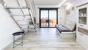 A modern interior with a staircase, a sofa, and a view to an outdoor terrace. - Tenerife Royal Gardens 23 - One Bed (Playa de las Américas)