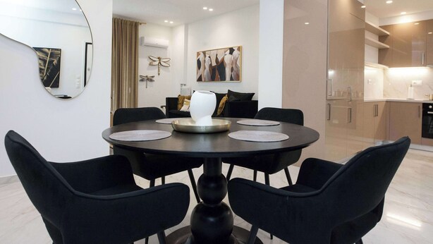 Una zona menjador moderna amb una taula rodona, cadires negres i un ramader decoratiu.