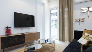 Un saló modern amb televisió de pantalla plana, una consola de fusta, una taula de cafè de vidre, un sofà negre i decoració mural d'aletres.