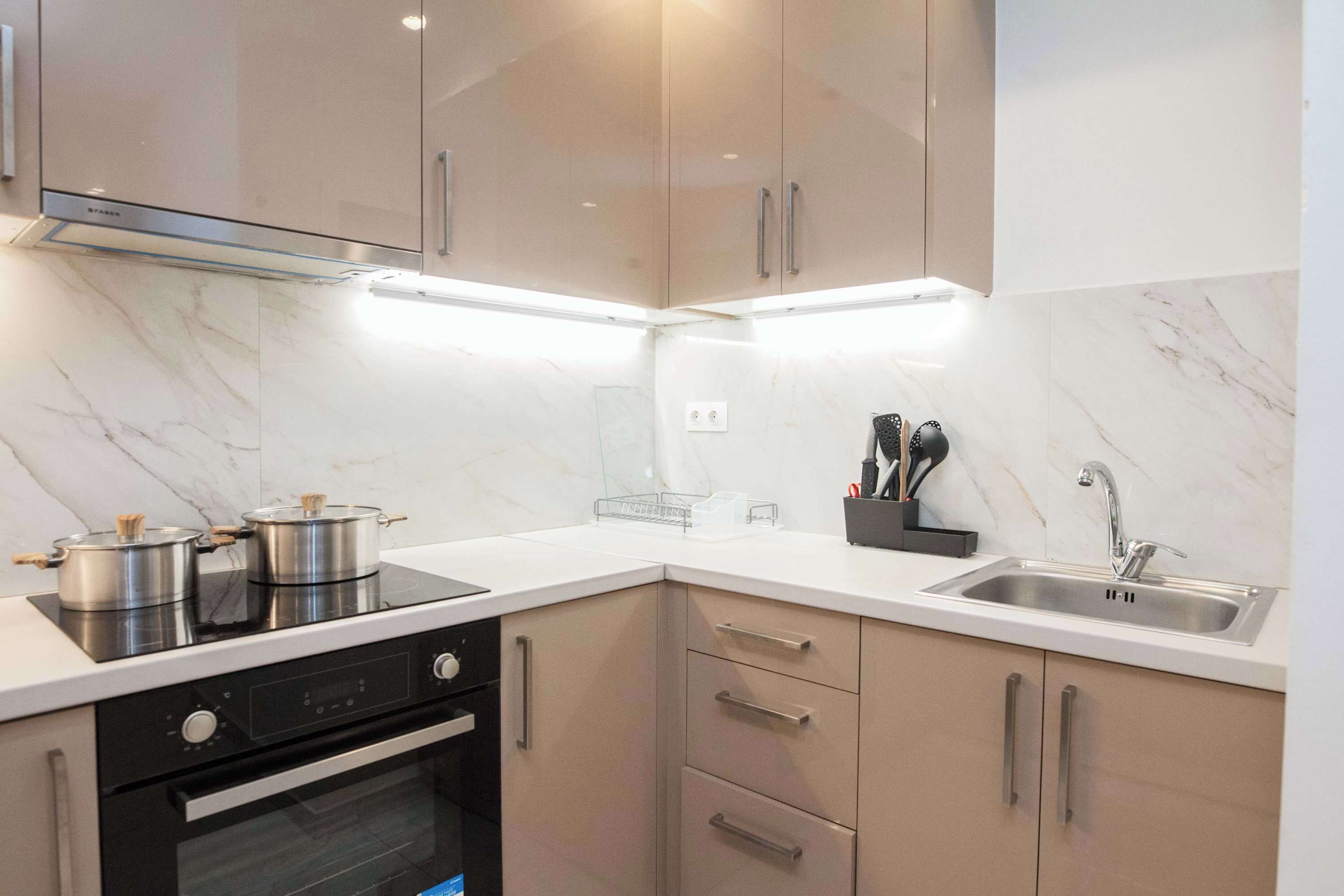 A modern kitchen with a built-in oven, a stove, and a sink.
