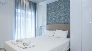 Una habitació d'hotel moderna amb un llit ben fet, un gran finestral amb cortines lleugeres i una paret amb dibuixos sobre el llit.