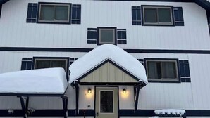 A multi-story building with a symmetrical facade, a central entrance with a door, and multiple windows. - Alpine Horn #2 ~ Sauna & Close to Powderhorn! (Bessemer)