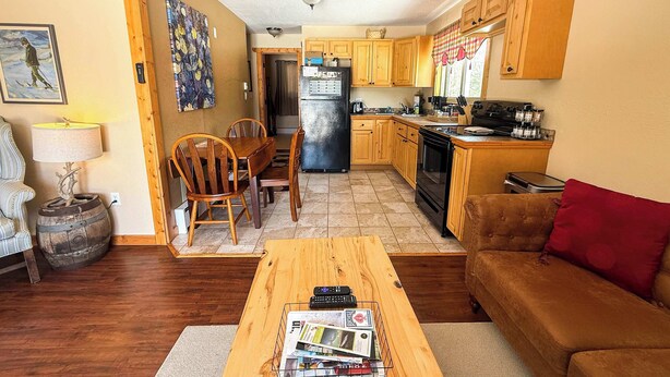 A cozy living room with a wooden coffee table, a brown sofa, and a dining area with wooden chairs and a table. - Alpine Horn #2 ~ Sauna & Close to Powderhorn! (Bessemer)